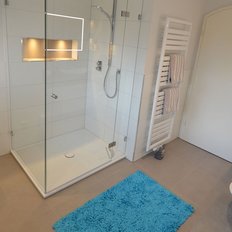 Helles Badezimmer mit eleganten Armaturen, einer Dusche und dekorativen Elementen wie Muscheln in Nischen.