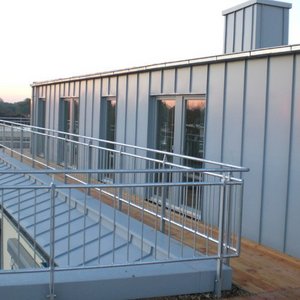Die Architektur des Gebäudes zeigt eine elegante Metallfassade und große Fenster, die den Raum mit Licht durchfluten.