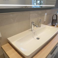 Ein helles Badezimmer mit einem großen, weißen Waschbecken und dekorativen Elementen wie einer kleinen Vase und Handtüchern.
