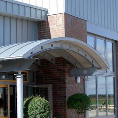 Die Fassade eines zeitgenössischen Gebäudes, das mit Ziegeln und Metall verkleidet ist, bietet einen einladenden Eingangsbereich.