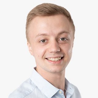 Ein junger Mann mit kurzem, blondem Haar lächelt freundlich in die Kamera, während er ein hellblaues Hemd trägt.