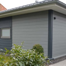 Ein neu gebautes, minimalistisches Haus mit einer glatten Fassade und einer kleinen Eingangstür auf der Seite.