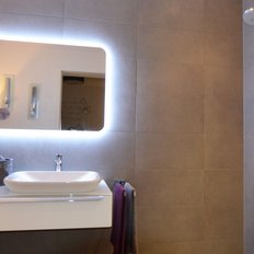 Ein modernes Badezimmer mit einem eleganten Waschbecken und einem beleuchteten Spiegel, umgeben von stilvollen Dekorationen.