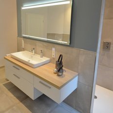 Ein modernes Badezimmer mit einem eleganten Waschbecken auf einem Holzregal und einem großen Spiegel über dem Waschbecken.