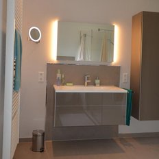 Ein modernes Badezimmer mit einem eleganten Waschbecken, einem großen Spiegel und einer Dusche im Hintergrund.