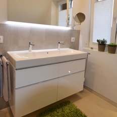 Ein modernes Badezimmer mit einem eleganten Doppelwaschbecken und stilvollen Armaturen, umgeben von hellen Wänden.