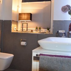 Ein modernes Badezimmer mit eleganter Einrichtung, einschließlich einer weißen Waschschüssel und stilvollen Wandlampen.